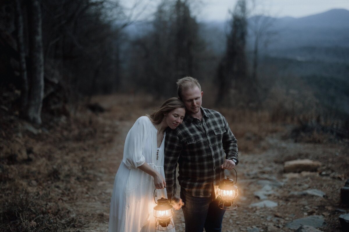 bride and groom standing on cliff with mountains in background