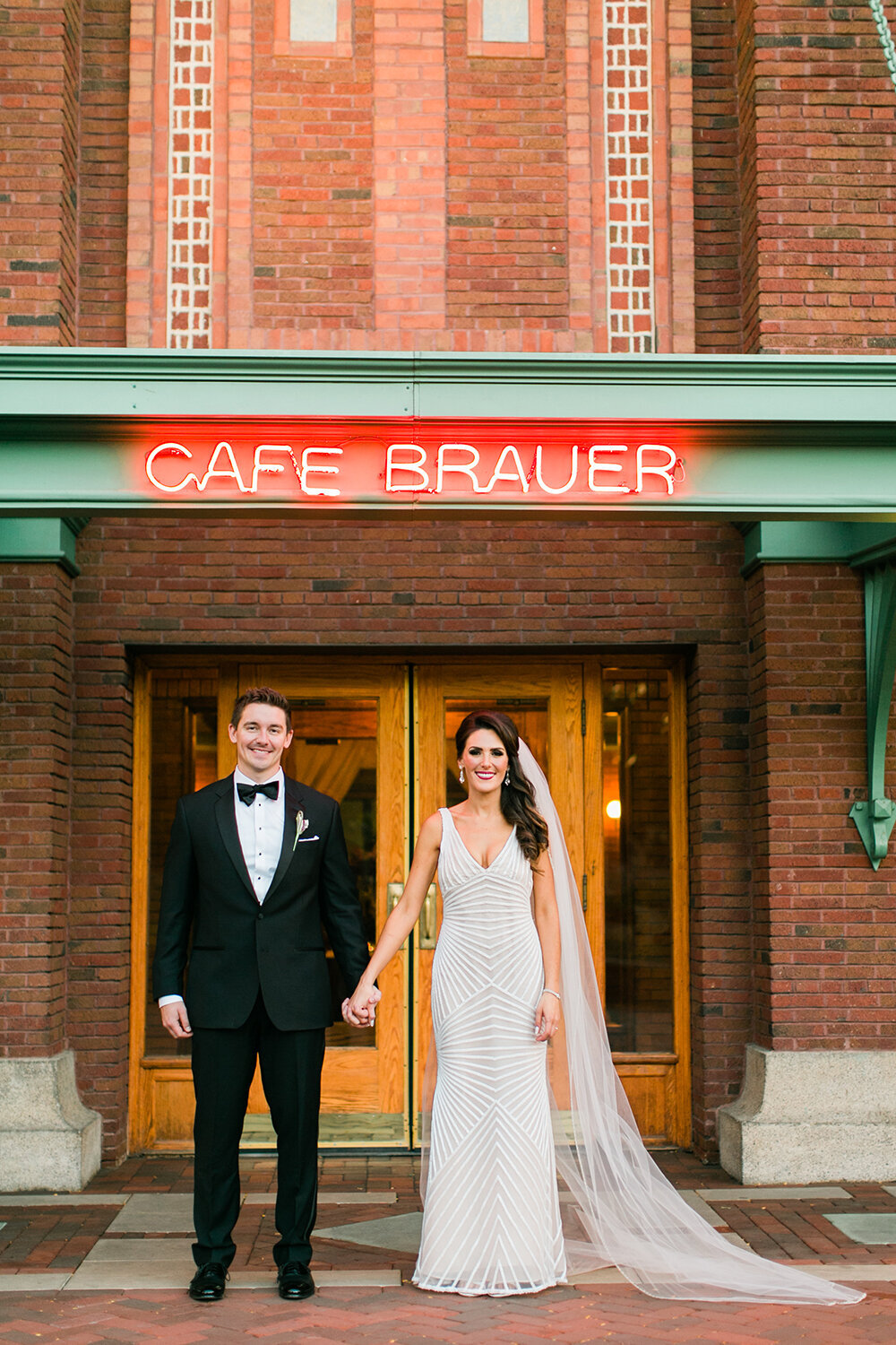 A couple pose in front of the Cafe Brauer entrance