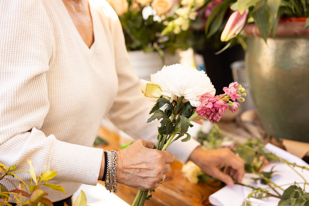 Woman arranging flowers on a wooden table