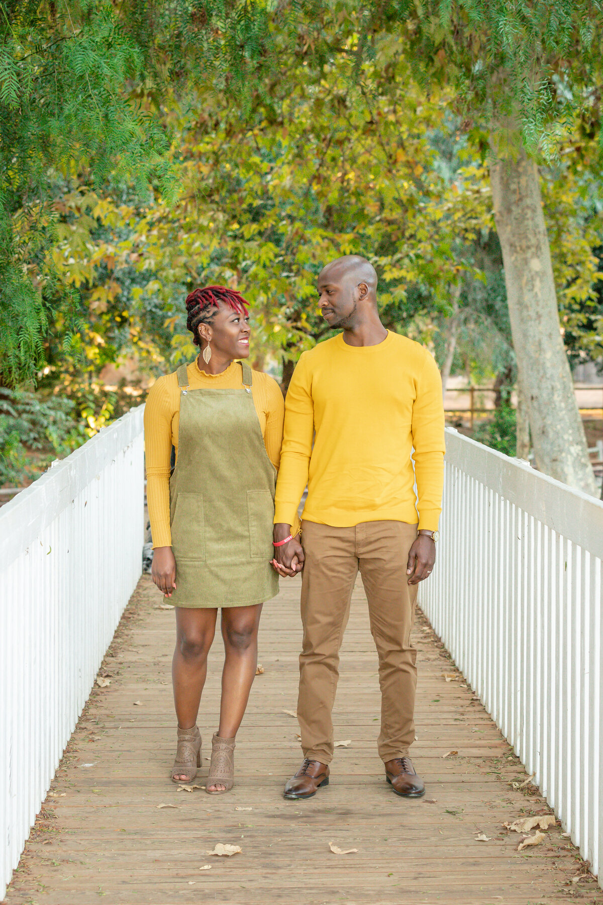 Black couple wearing yellow and green smiling on a bridge