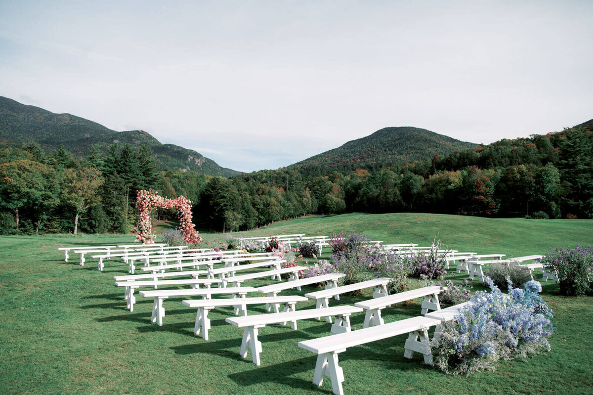 An outdoor wedding ceremony set-up with an arch and aisle full of flowers at The Ausable Club, NY. Image by Jenny Fu Studio.