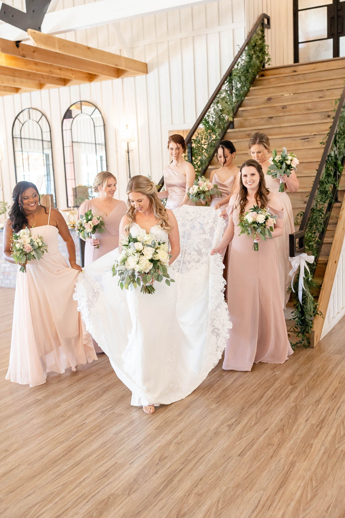 bridesmaids in pink carry train of dress  down stairs at Milestone Georgetown Texas  wedding