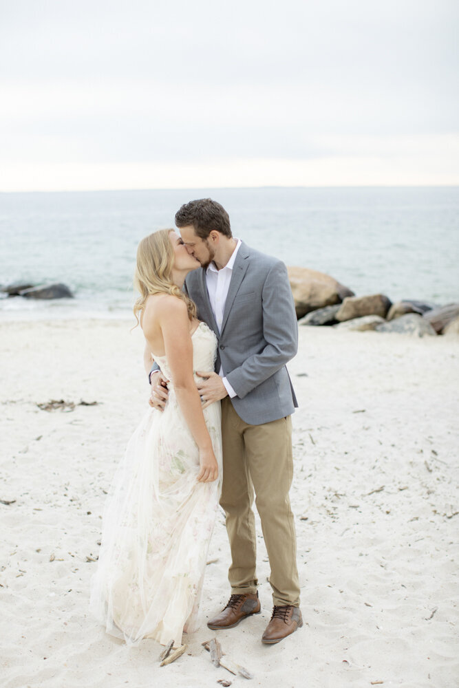 engaged couple kisses on beach for engagement photos