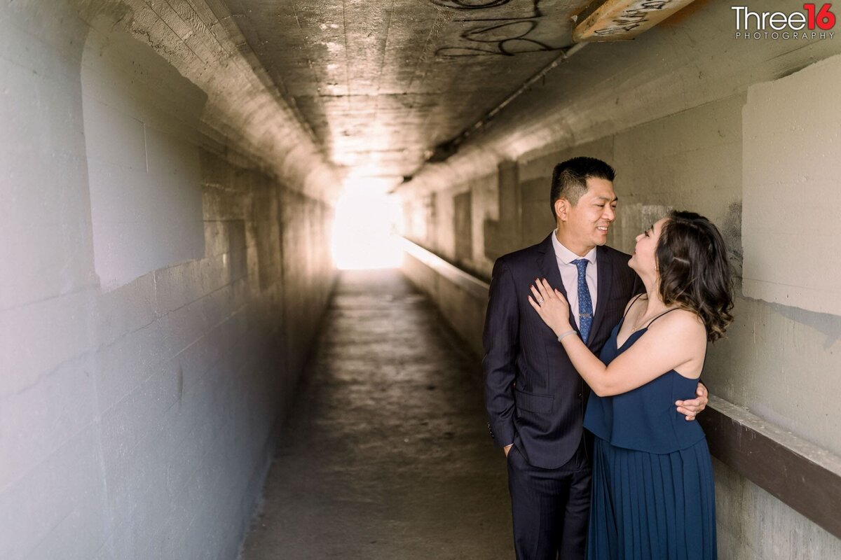 Engaged couple gaze into each other's eyes in an underground walkway