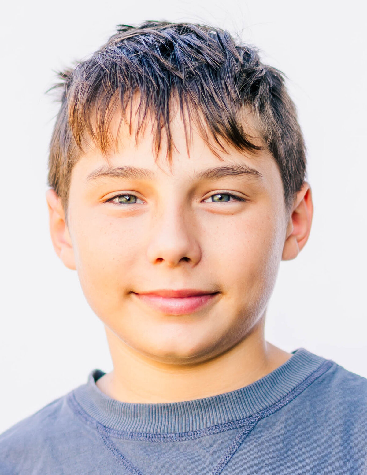 8th-grade boy with confident smile on white backdrop — fine art school portrait