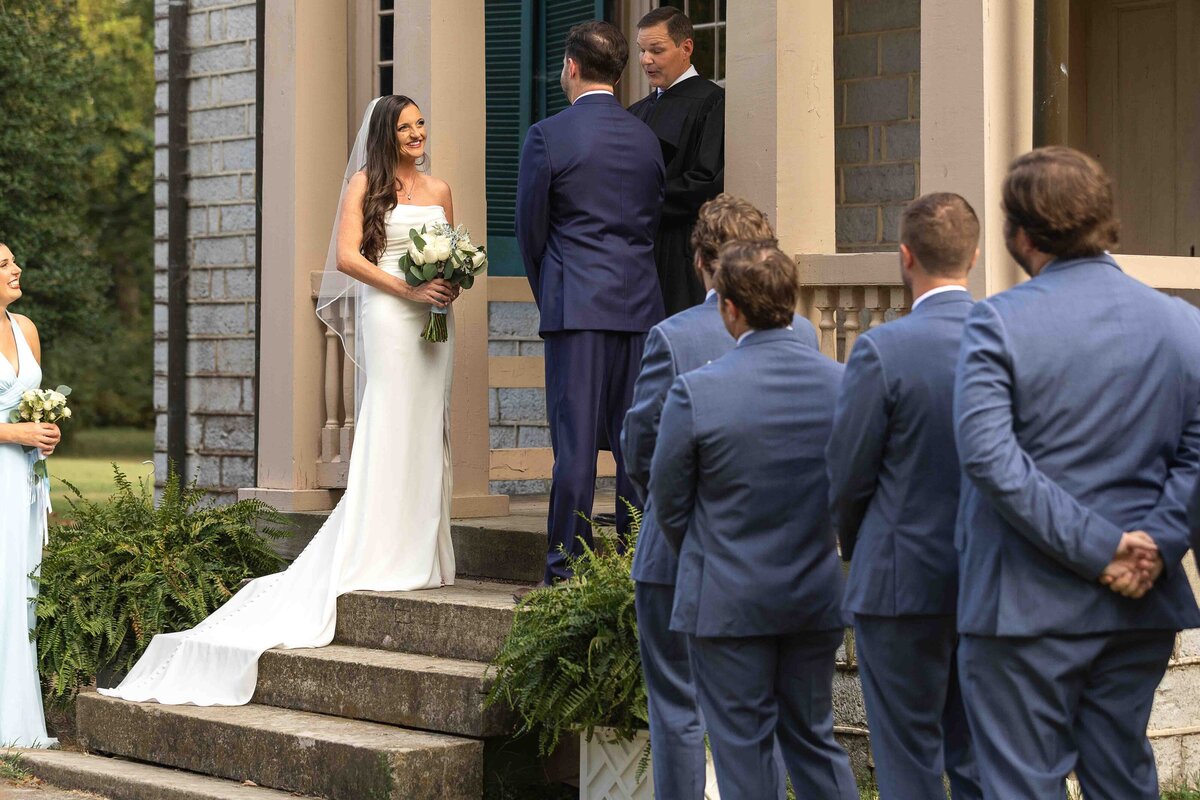 Bride smiling at groom at wedding alter while holding bridal bouquet 