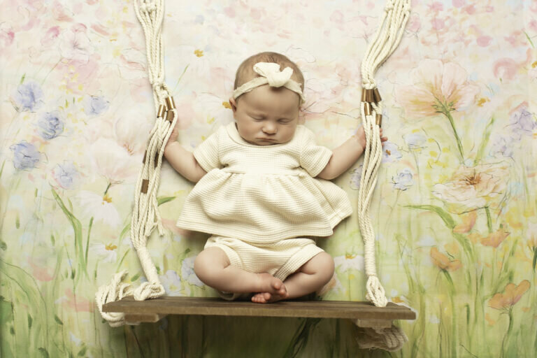 Young girl sitting on a charming swing, surrounded by a beautiful floral backdrop, creating a dreamy and whimsical portrait
