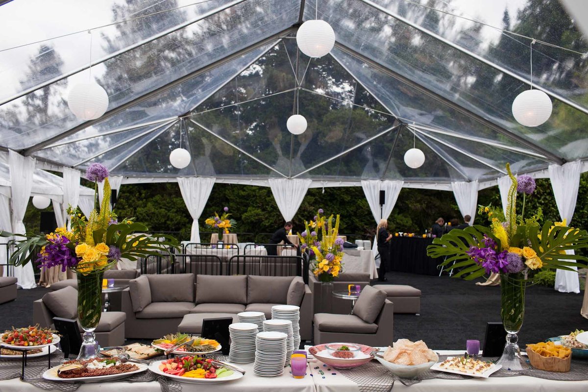 company launch party in large clear tent with yellow and purple flowers