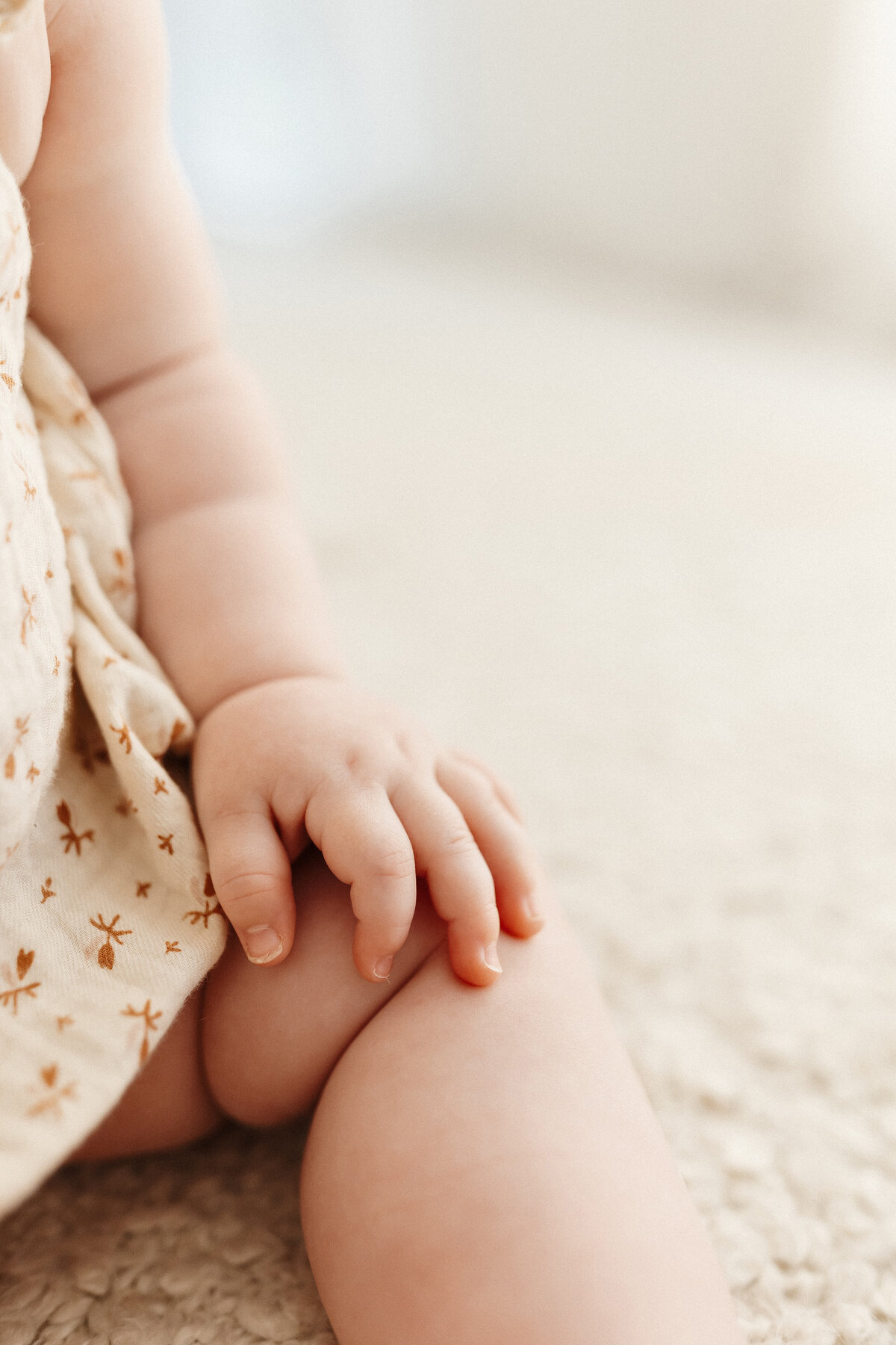 A close up of a babies chubby hands and legs during a milestone photoshoot with christchurch photographer lucy jane