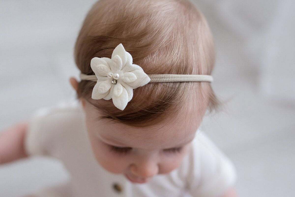baby looking down with a flower bow in hair
