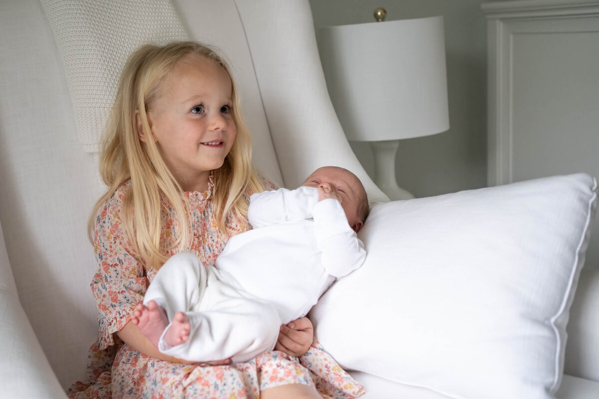 Big sister holding baby sister in rocking chair