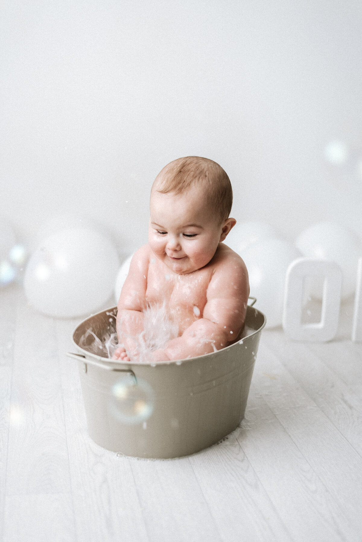 baby splashing water in a tub at first birthday photoshoot in billingshurst