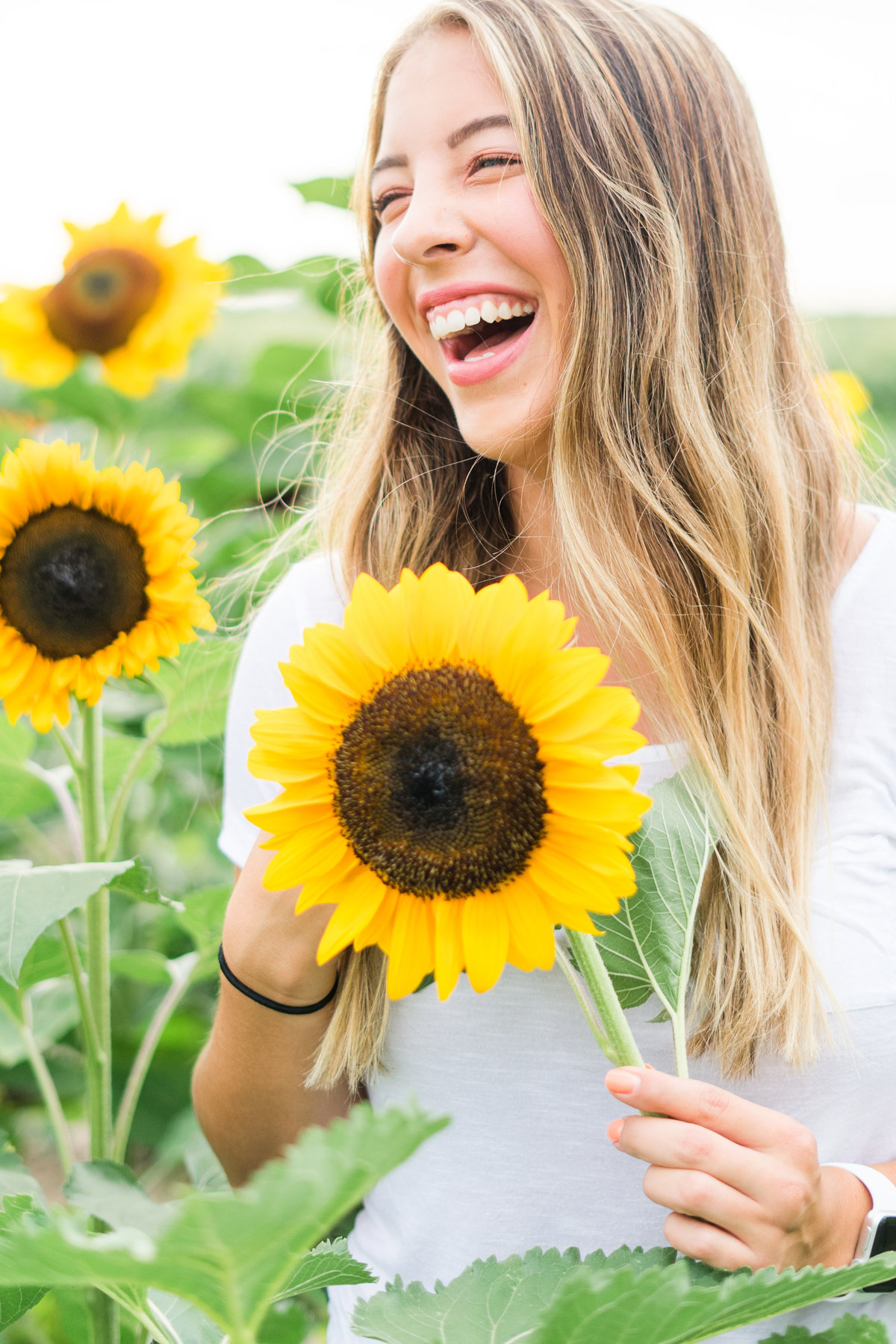 Senior girl holding sunflower laughing