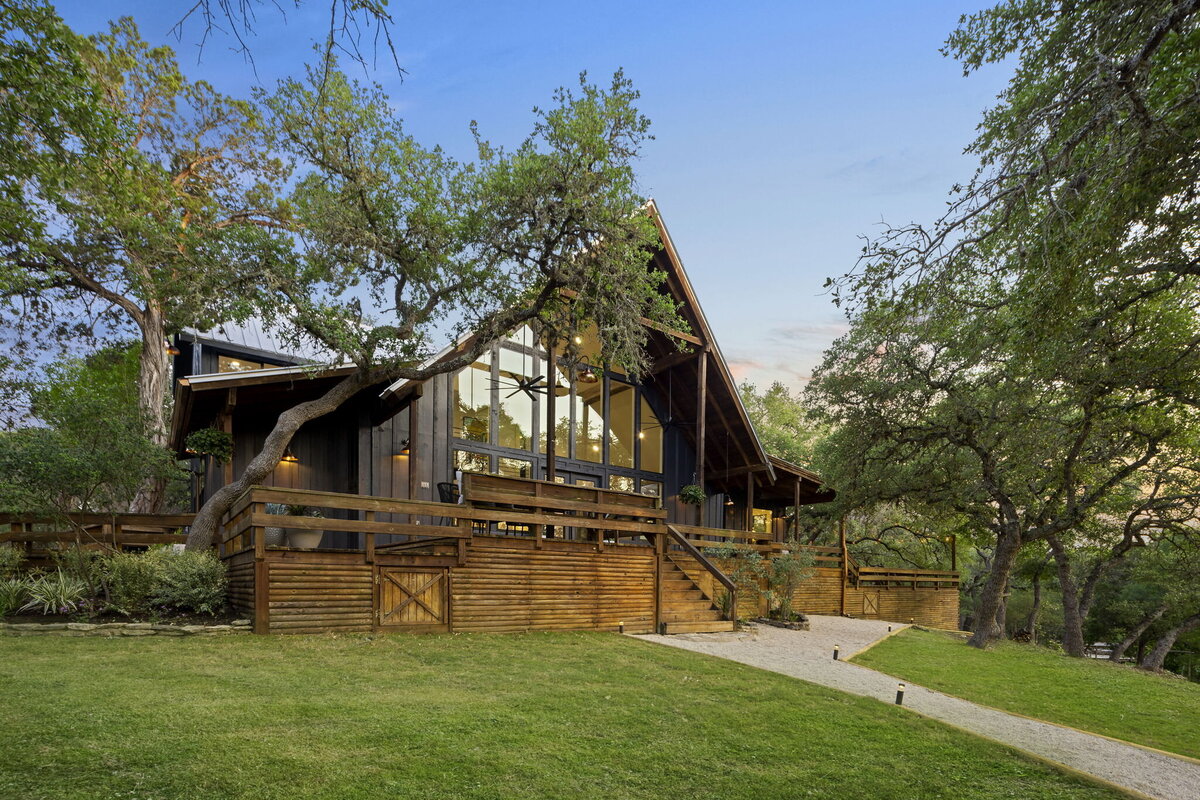 Exterior of a large home with green lawn and surrounding trees