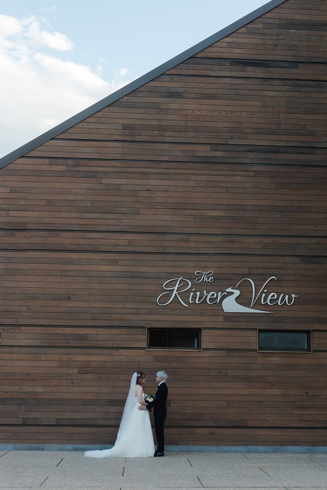 Bride and groom in front of river view sign