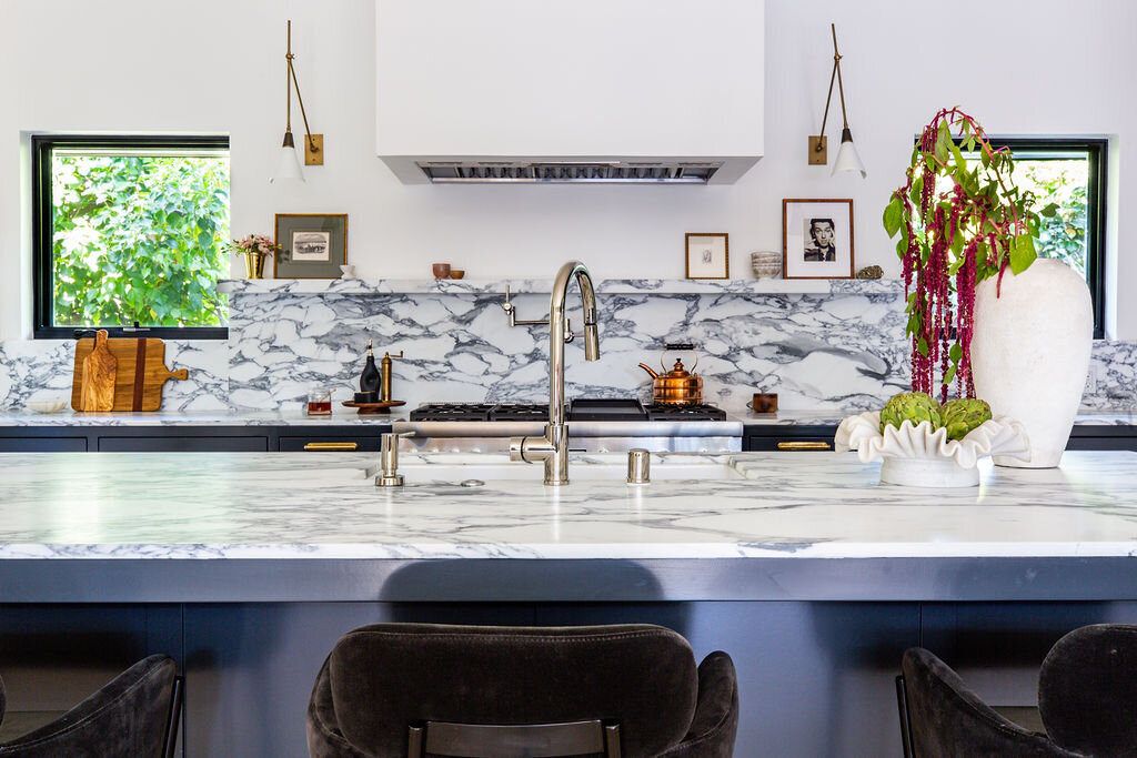 Kitchen with dark navy cabinets, Corchia marble countertops and backsplash, and marble shelf