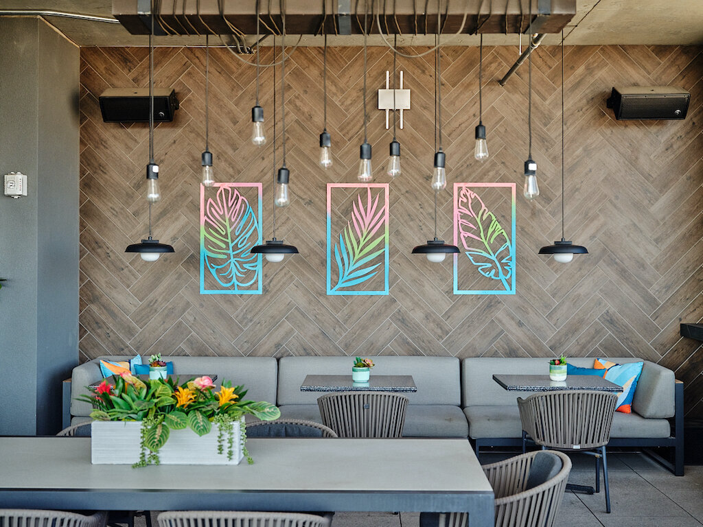 The second rooftop terrace with a wooden feature wall with neon leaf art and a couch for guests