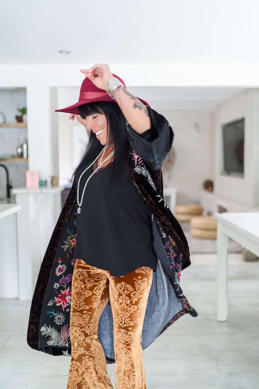 funky woman in robe and red hat dancing in modern living room for creative branding session