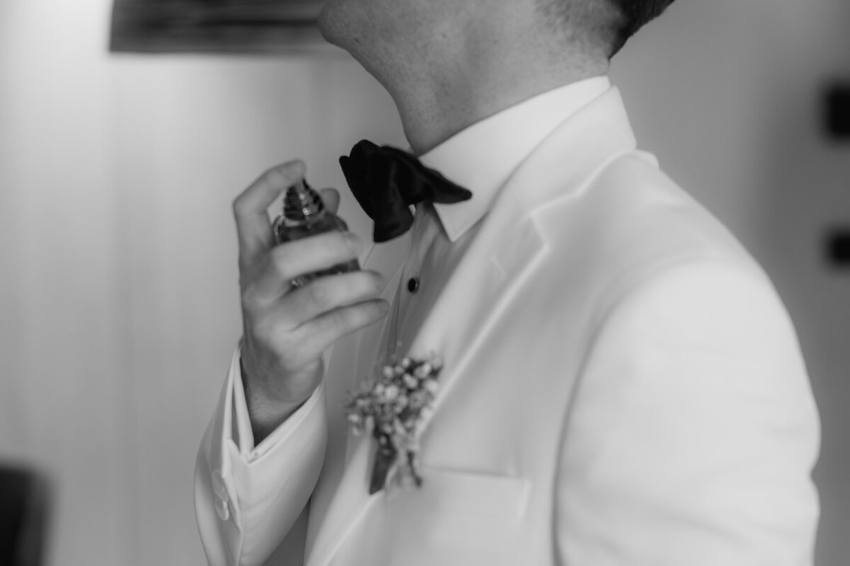 Der Bräutigam legt einen Spritzer Parfüm auf um seinem Outfit den letzten Schliff zu geben.