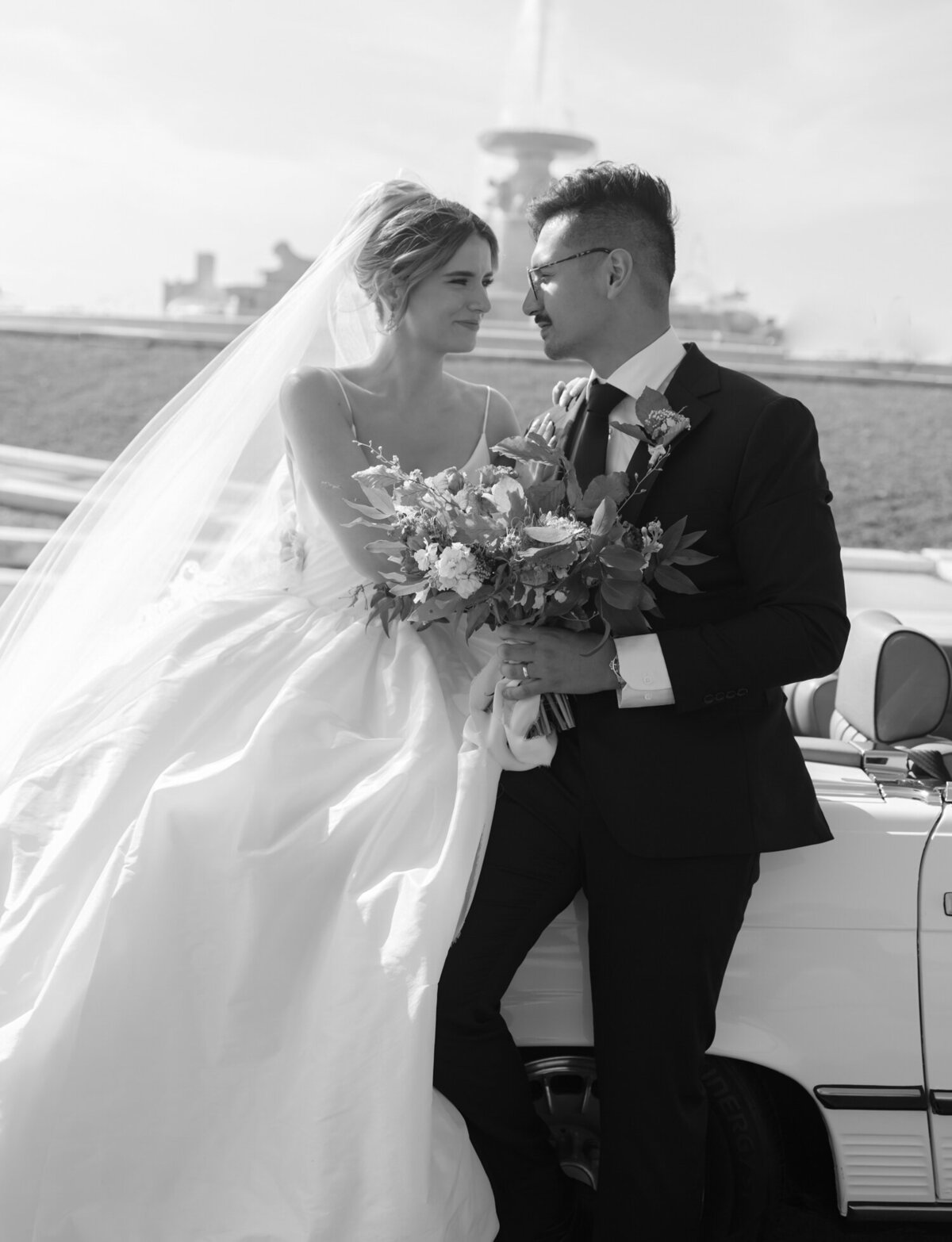 candid, natural wedding photographer in Detroit, Christina Harrison, captures bride and groom with vintage car on Belle Isle with fountain