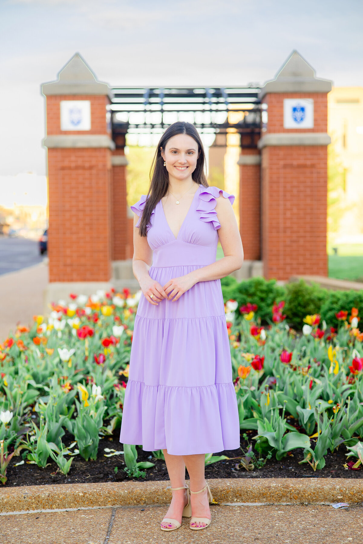 beautiful college senior at SLU in purple dress in a bed of tulips