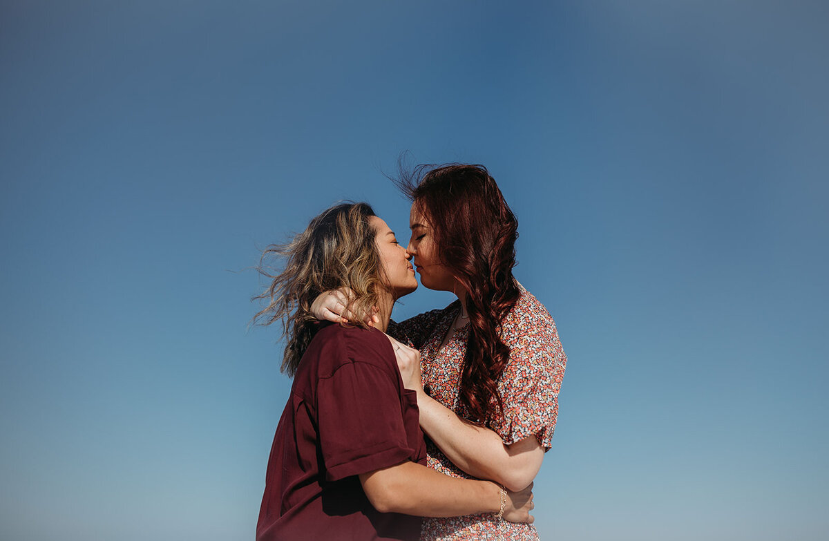 A couple kissing against a clear blue sky