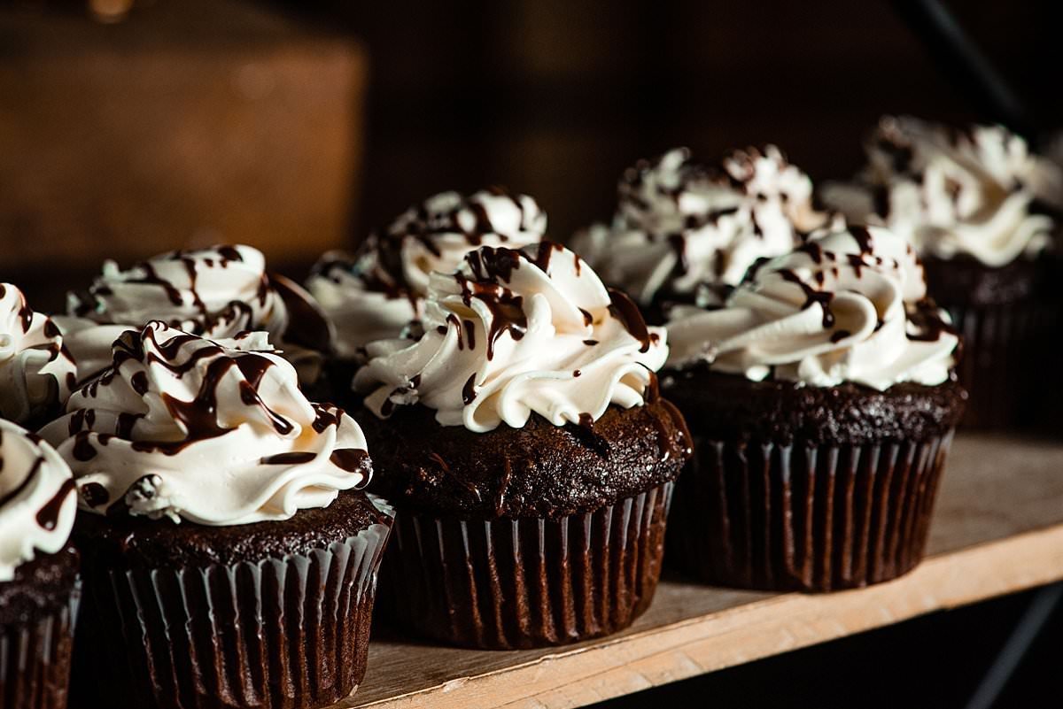 Close up photo of chocolate cupcakes with vanilla frosting and chocolate drizzle