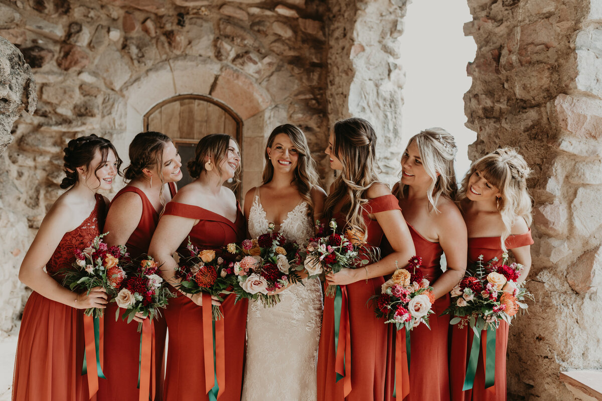 Bridesmaids pose with the bride in rust colored dresses at Cherokee Ranch and Castle.