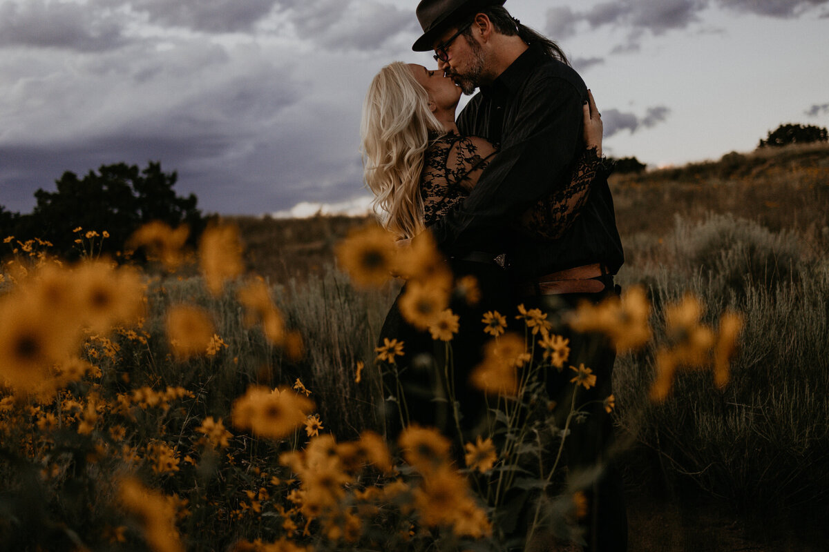 new bride and groom kissing in the middle of a wild flower field