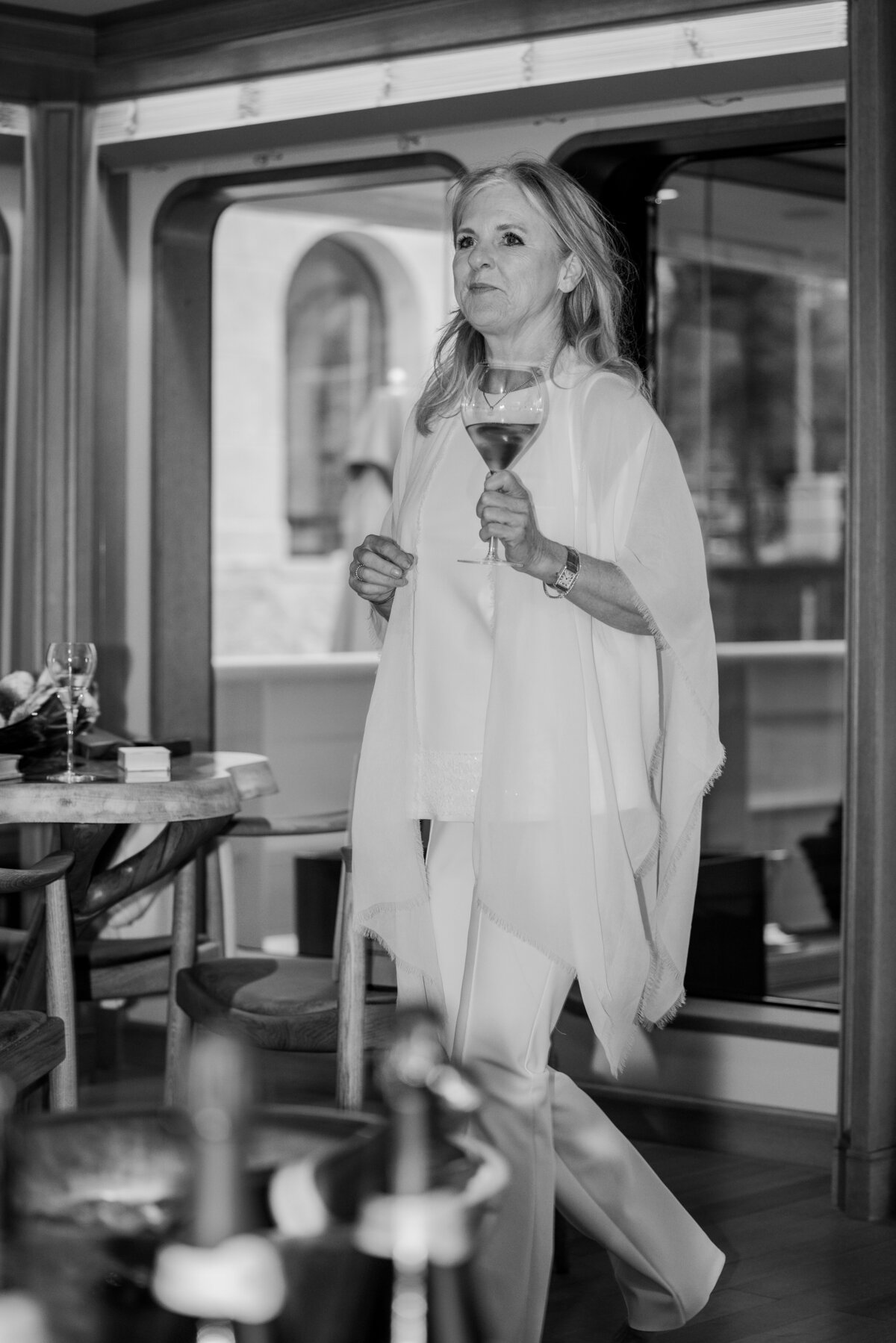 A guest gracefully walks through the refined interior of the Samadhi yacht, wine glass in hand, during an exclusive event at the Scheepvaartmuseum, Amsterdam. This image is perfect for promoting luxury event photography services.