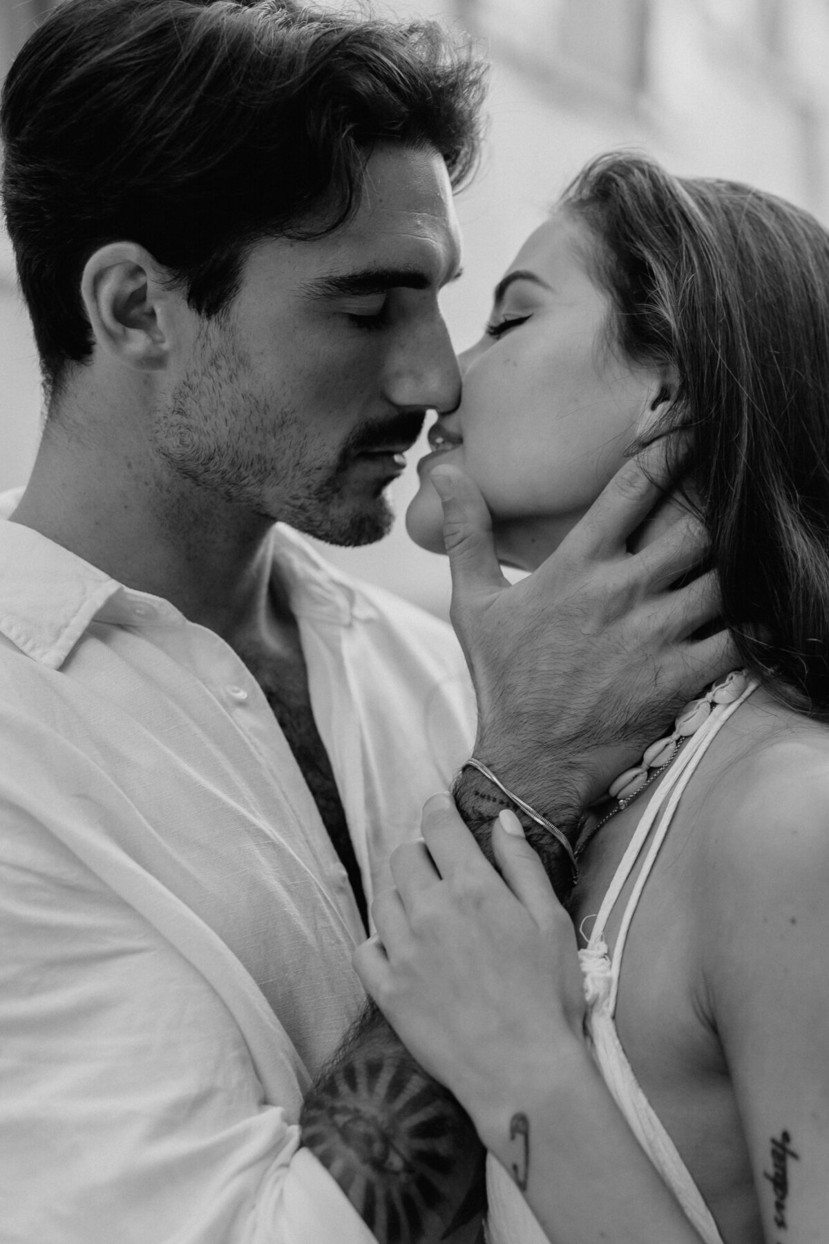 Black and white photo of couple upclose about to kiss with his hand on her neck.