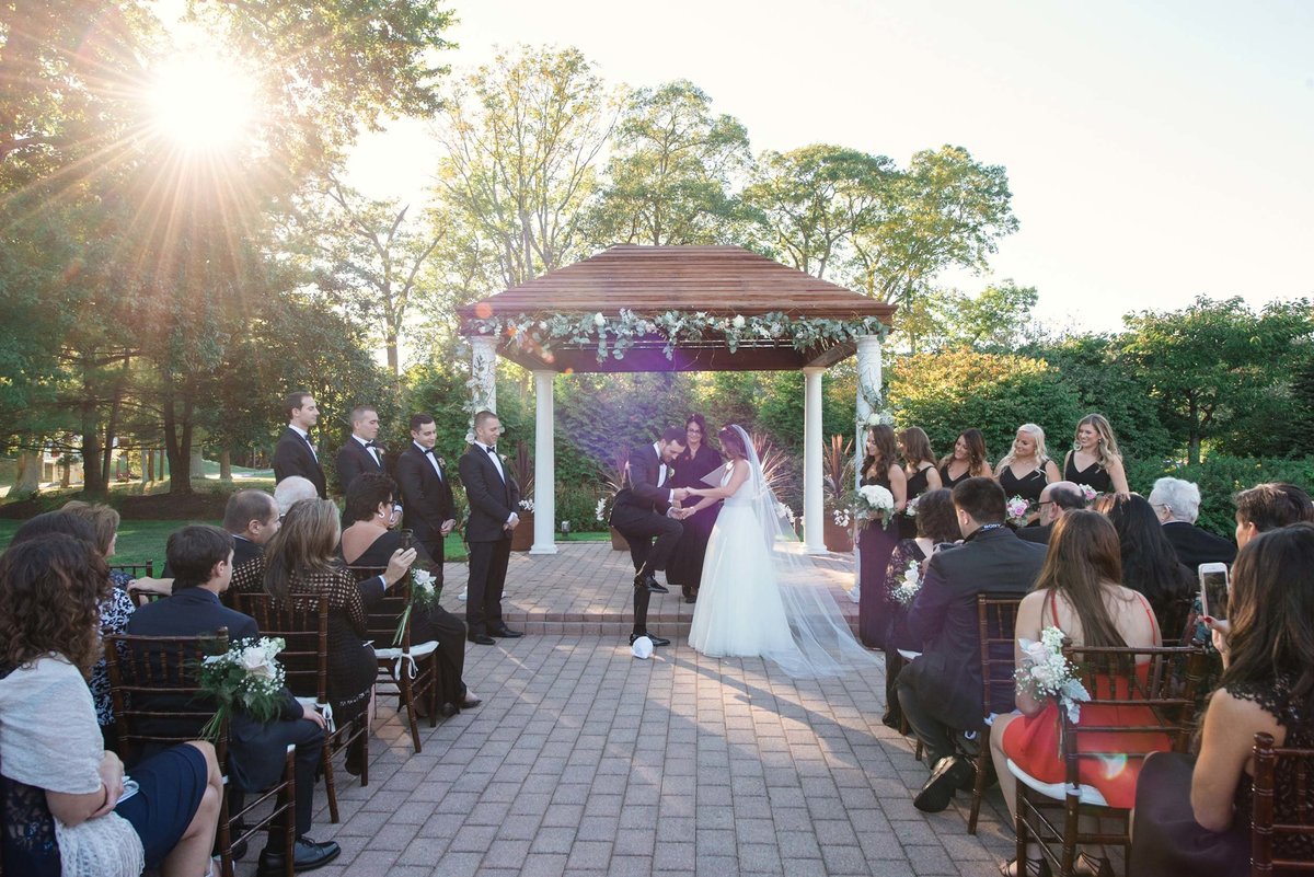 Bride and groom at the altar holding hands with sun shining on them at Stonebridge Country Club