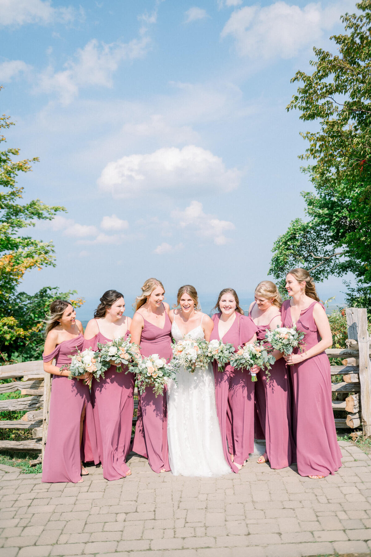 Bridesmaids holding flowers looking at bride