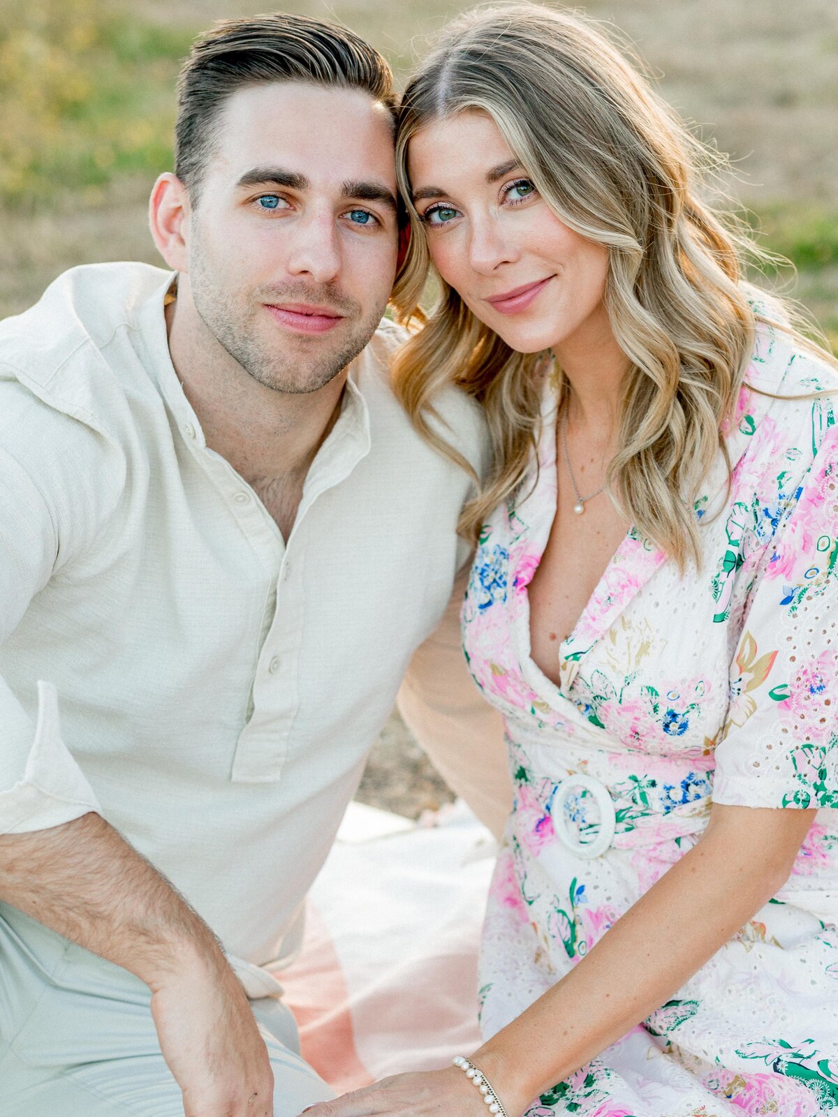 Engaged couple smiling during outdoor picnic session
