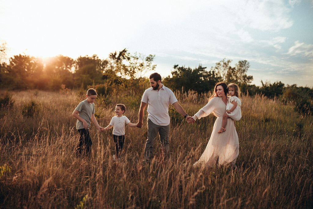 family holding hands walking in field