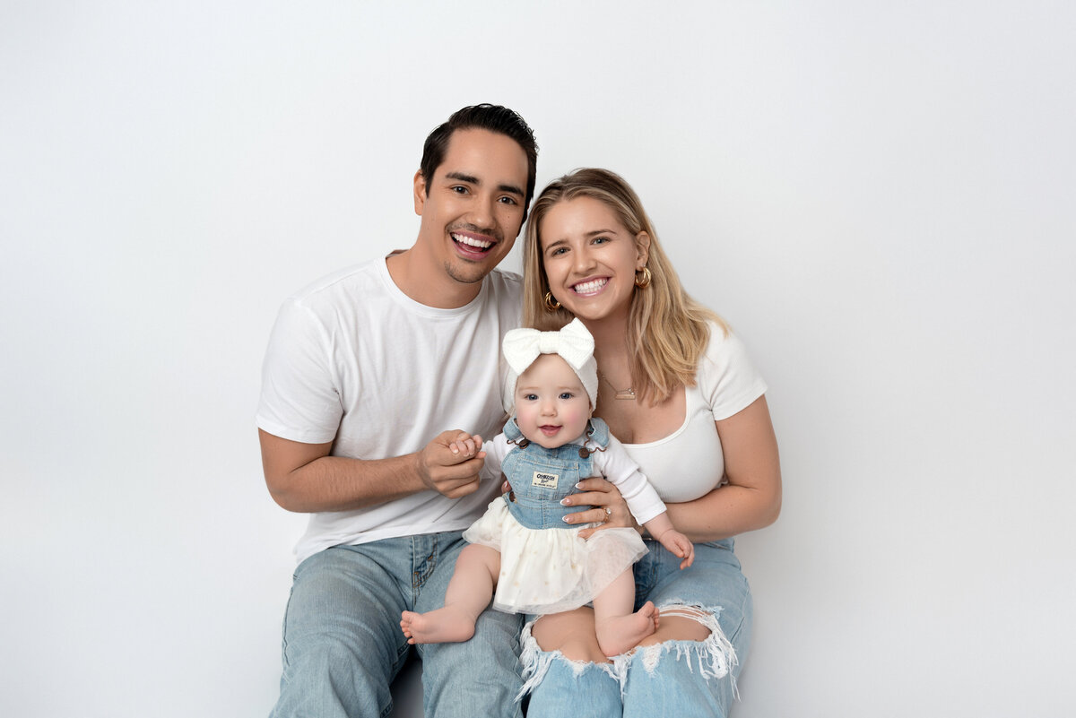 Parents holding their baby and smiling during an Infant Photoshoot