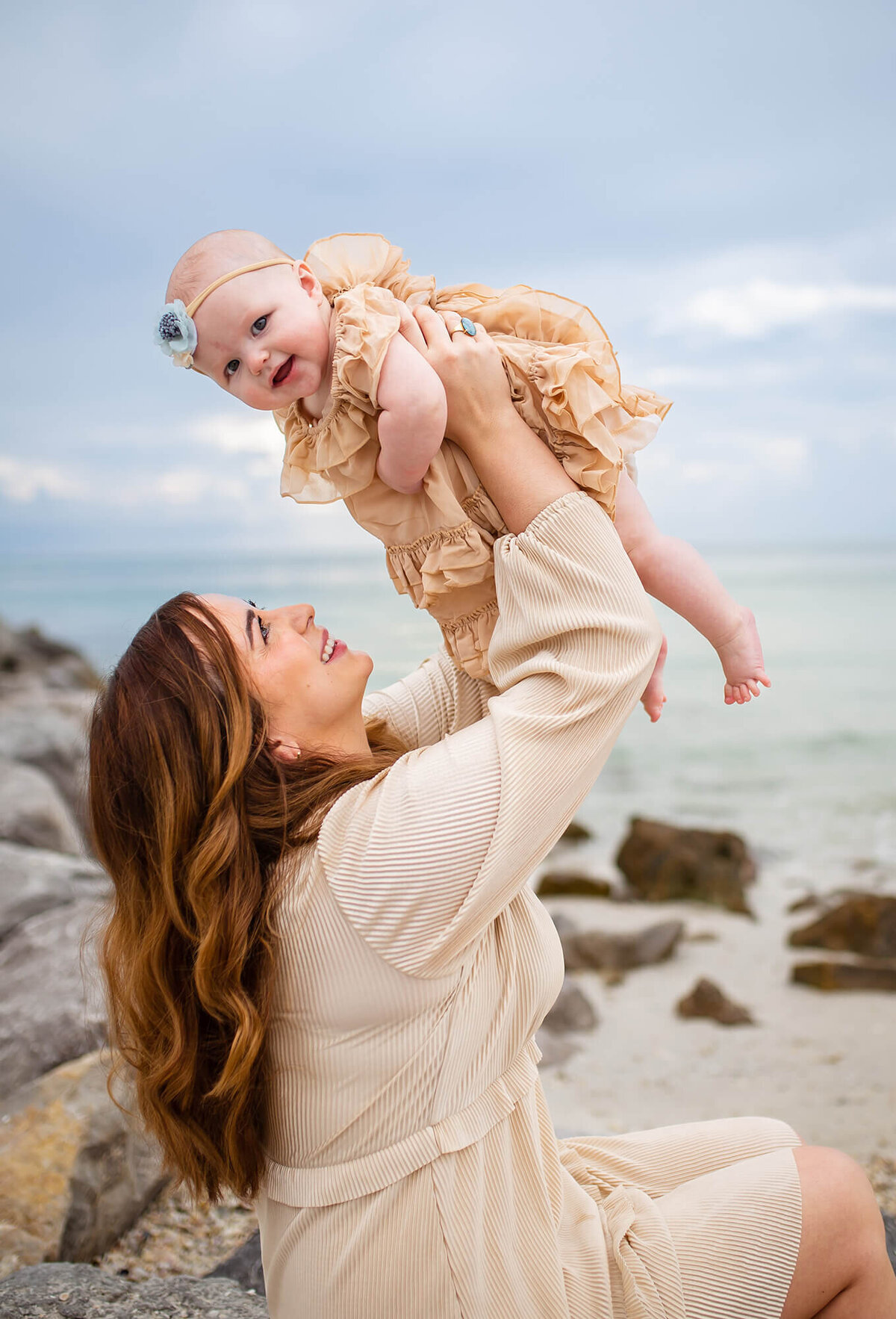Mother playing with baby girl while sitting on the rocks at Passe Grille Beach in St Petersburg FL 