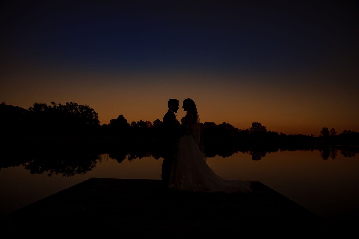 bride-and-groom-silhouetted-by-orange-and-blue-sunset