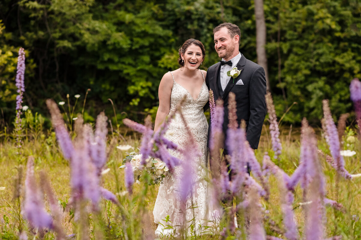 Purple floowers in front of a bride and groom outside