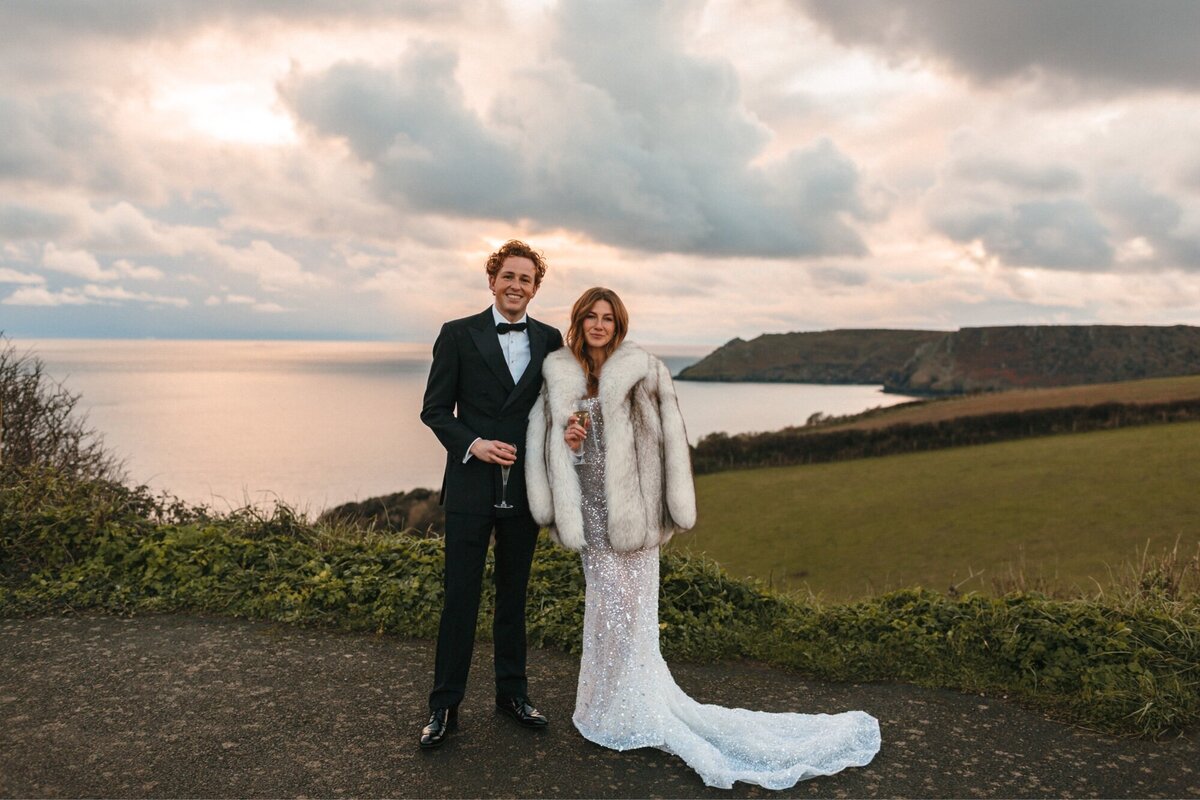 Bride and groom by the sea at their stylish winter wedding