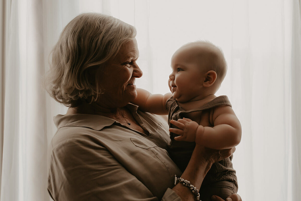 A grandma and Grandson look at each other in front of a window
