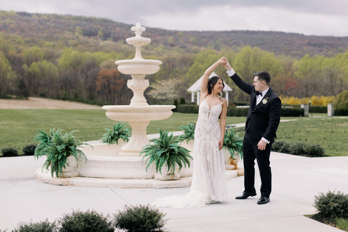 Bride and groom dance outside near a fountain at their lavish spring wedding