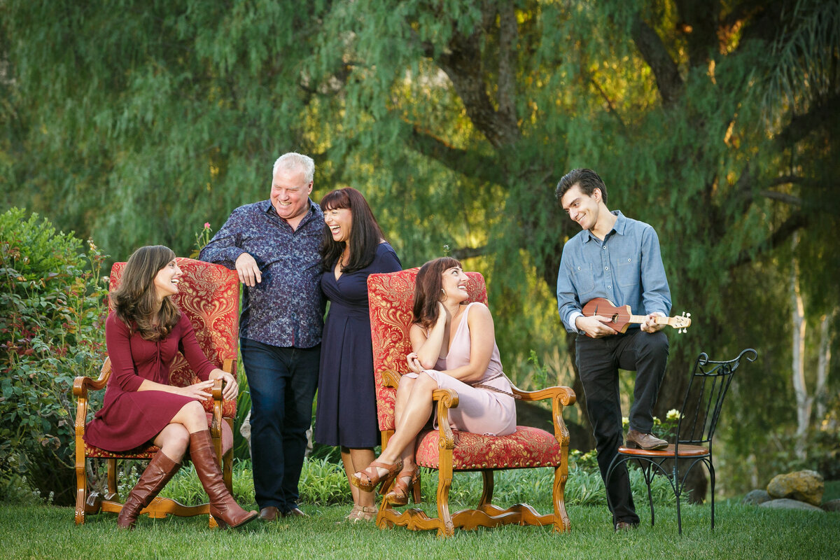 Parents and their adult children sitting and standing together laughing