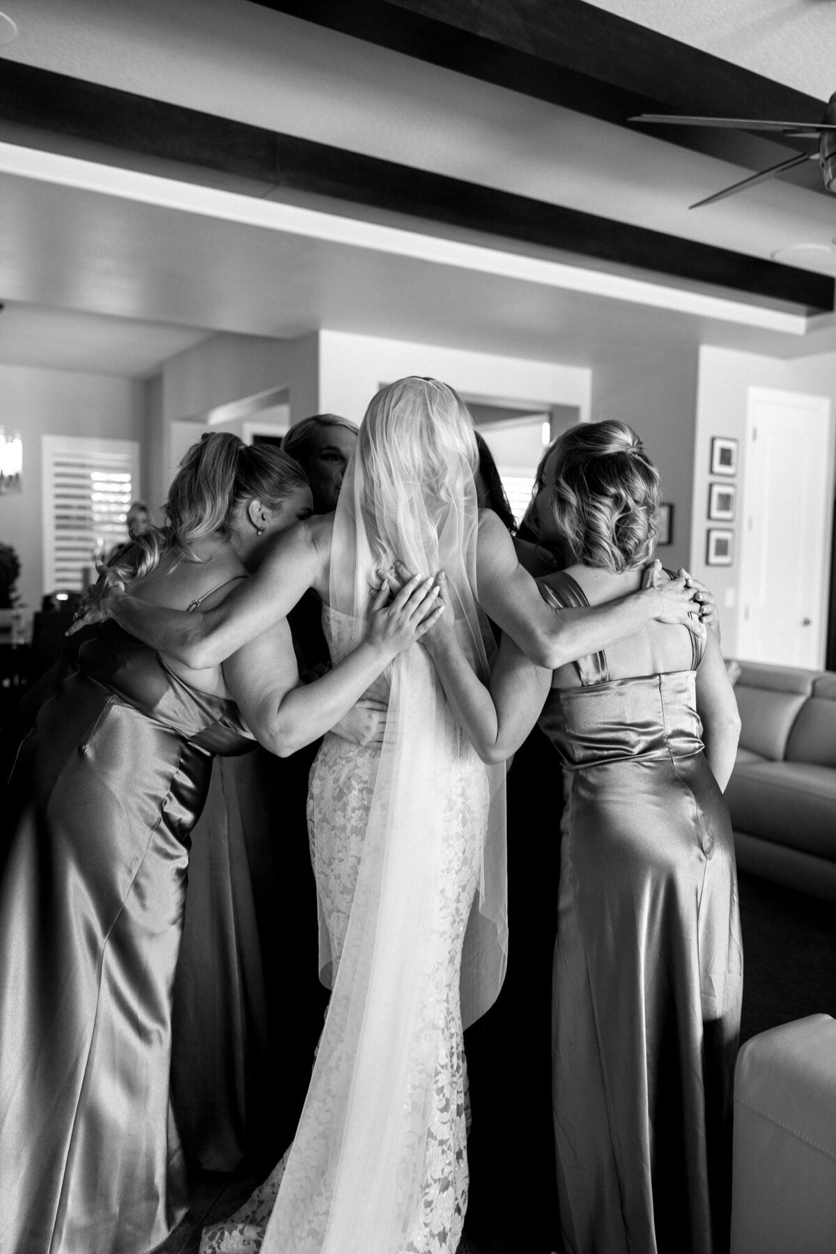 Bridesmaids hugging bride after seeing her in wedding dress