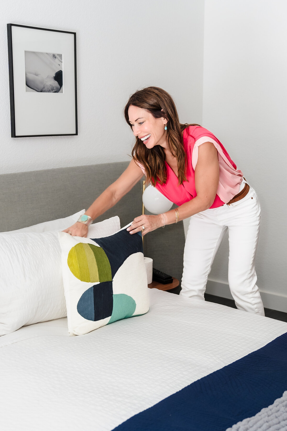 realtor staging a bedroom, placing a pillow in the bed