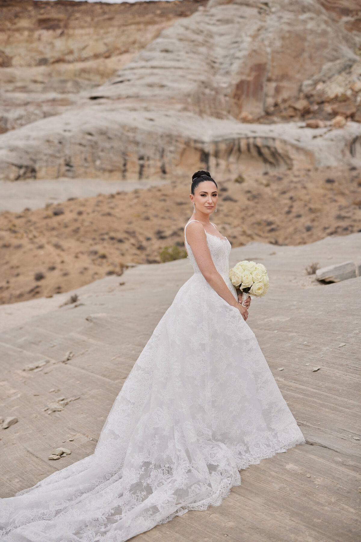 Bride on rock formation holding flowers at Amangiri Utah