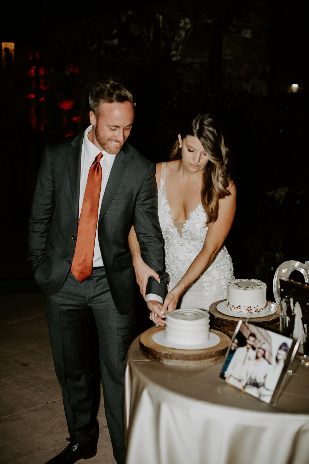 Bride and groom cut their white wedding cake at their wedding reception.