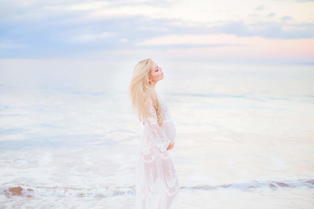 Pastel Maui babymoon portrait with blonde woman in white lace dress photographed at sunrise in Wailea