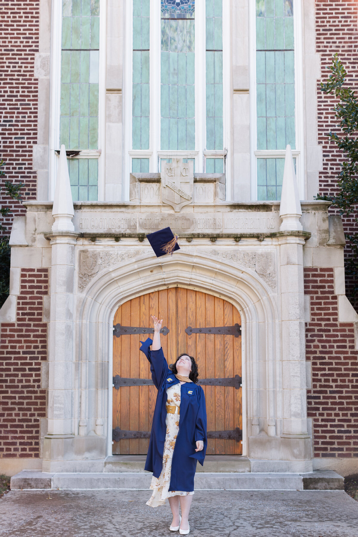college senior throwing her hat in the air in front of Patten Chapel at UTC