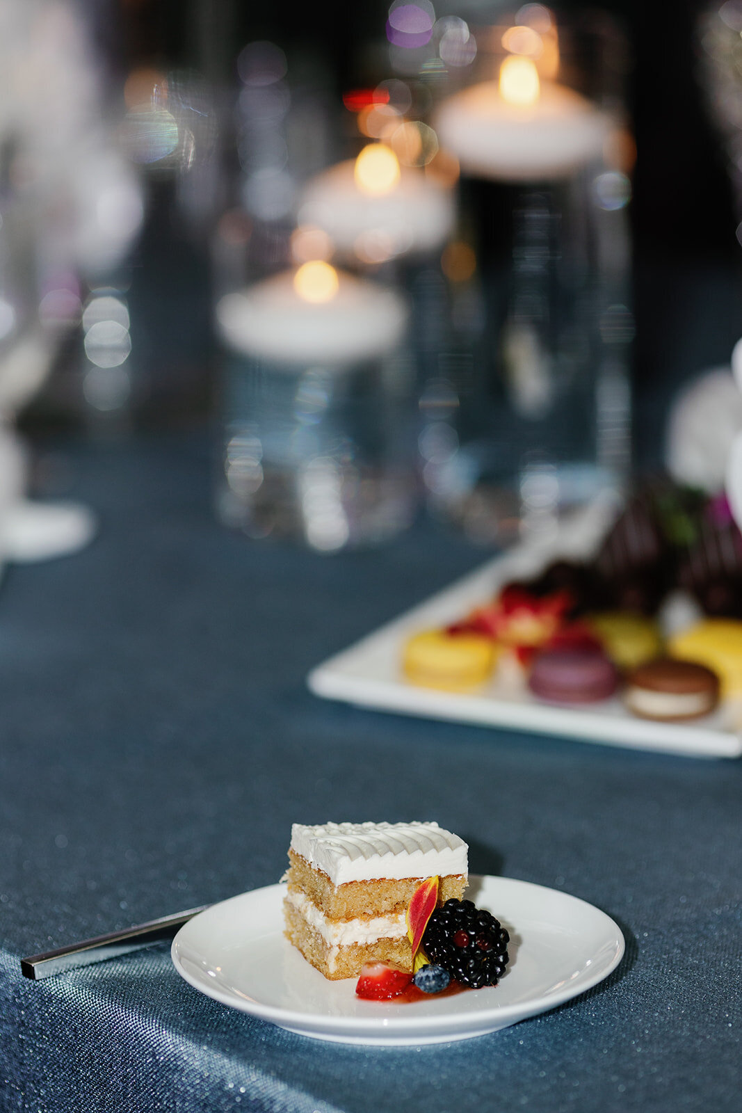 A delicate dessert plate featuring a slice of layered cake garnished with fresh berries, set against a backdrop of glowing candlelight at Ocean Reef in Key Largo.